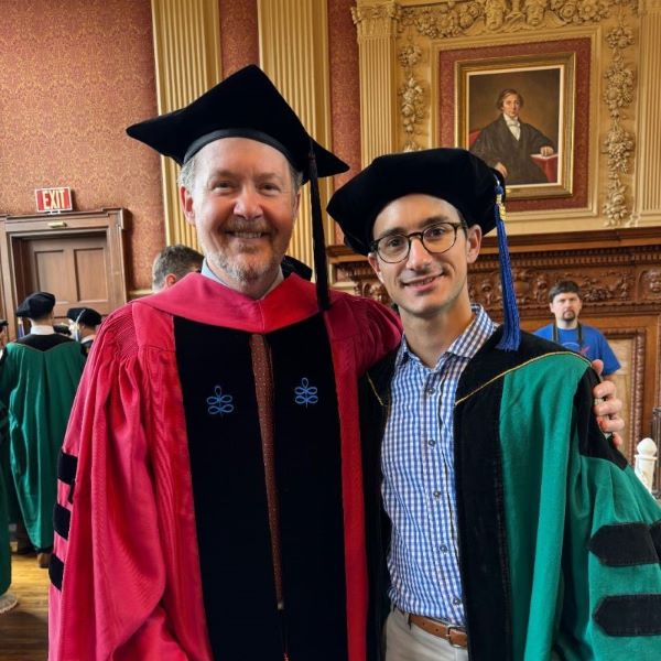 Former Weidenbaum Center Graduate Affiliate and PhD recipient Benjamin Noble carries banner at 2024 Wash U Commencement ceremony